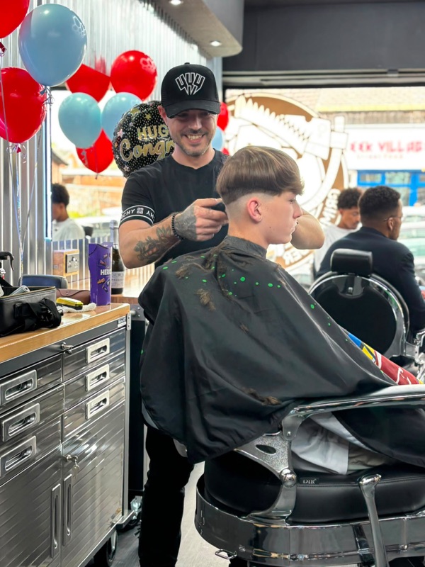 Grim finishing a young client's cut in the new shop